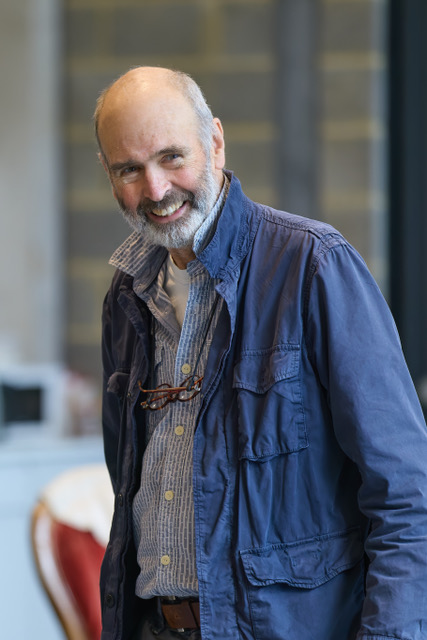 Smiling man in blue jacket standing indoors