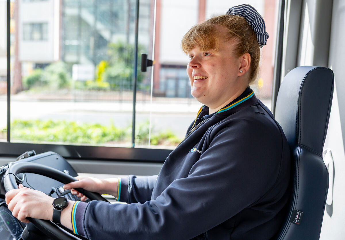 Smiling bus driver in uniform at wheel of modern bus