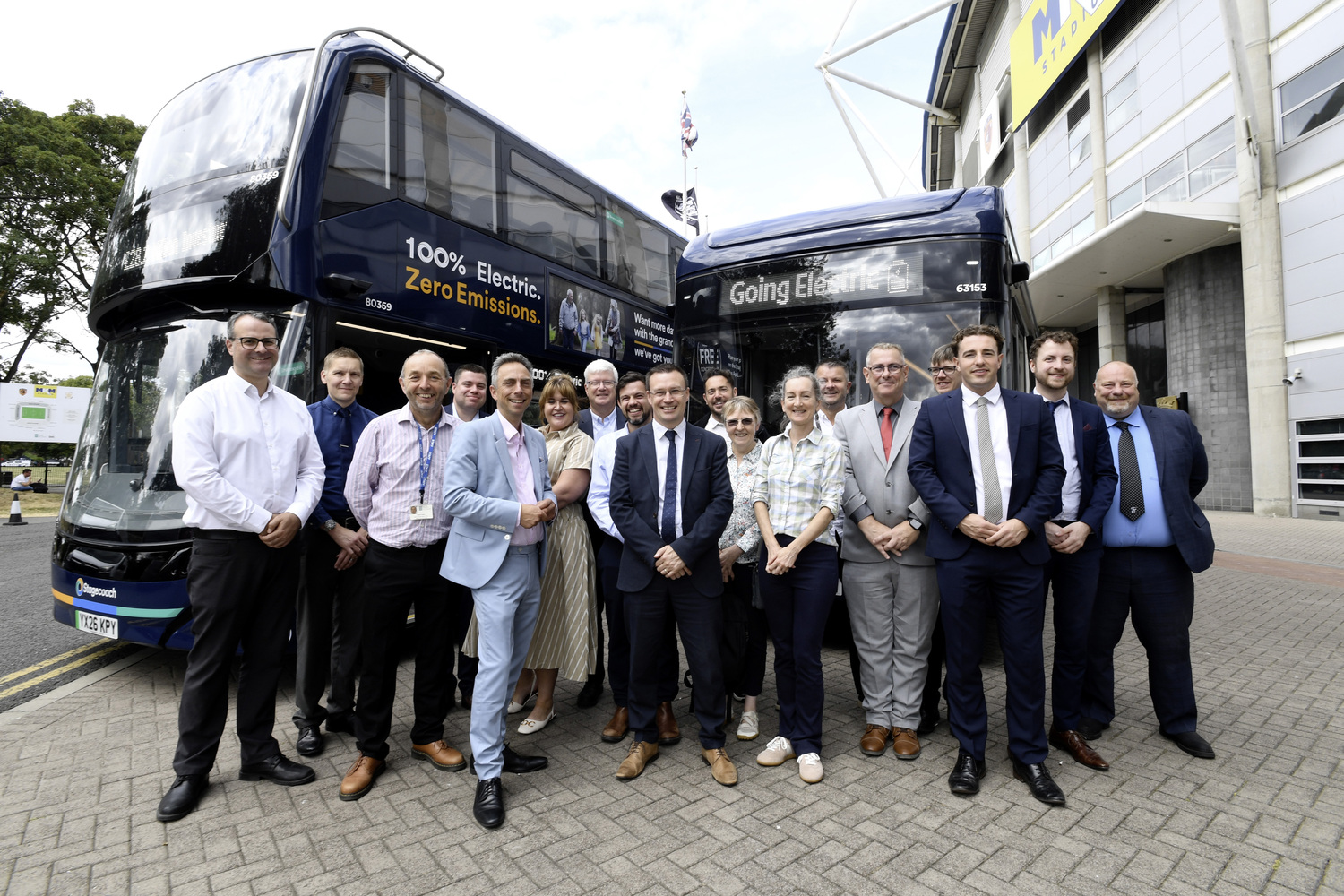 Group of people standing in front of two electric buses