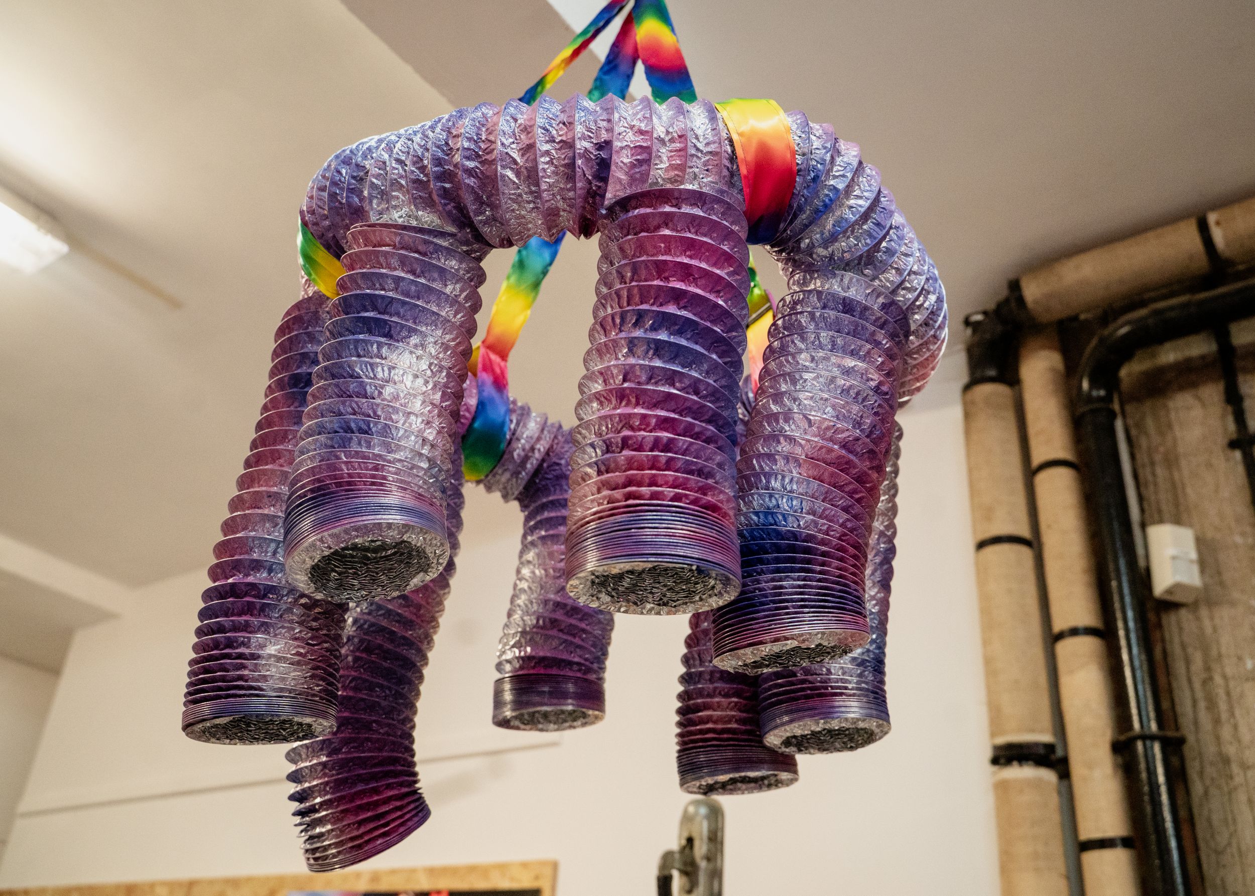 Colourful slinky chandelier hanging from a ceiling indoors