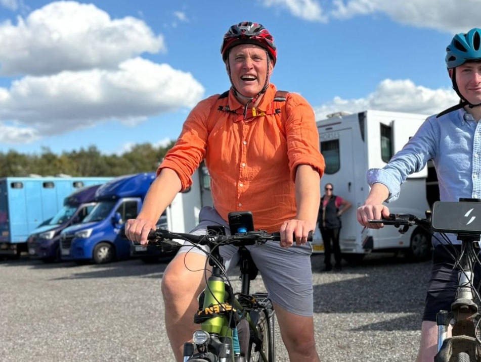 Two cyclists in bright clothing on a sunny day at a caravan park