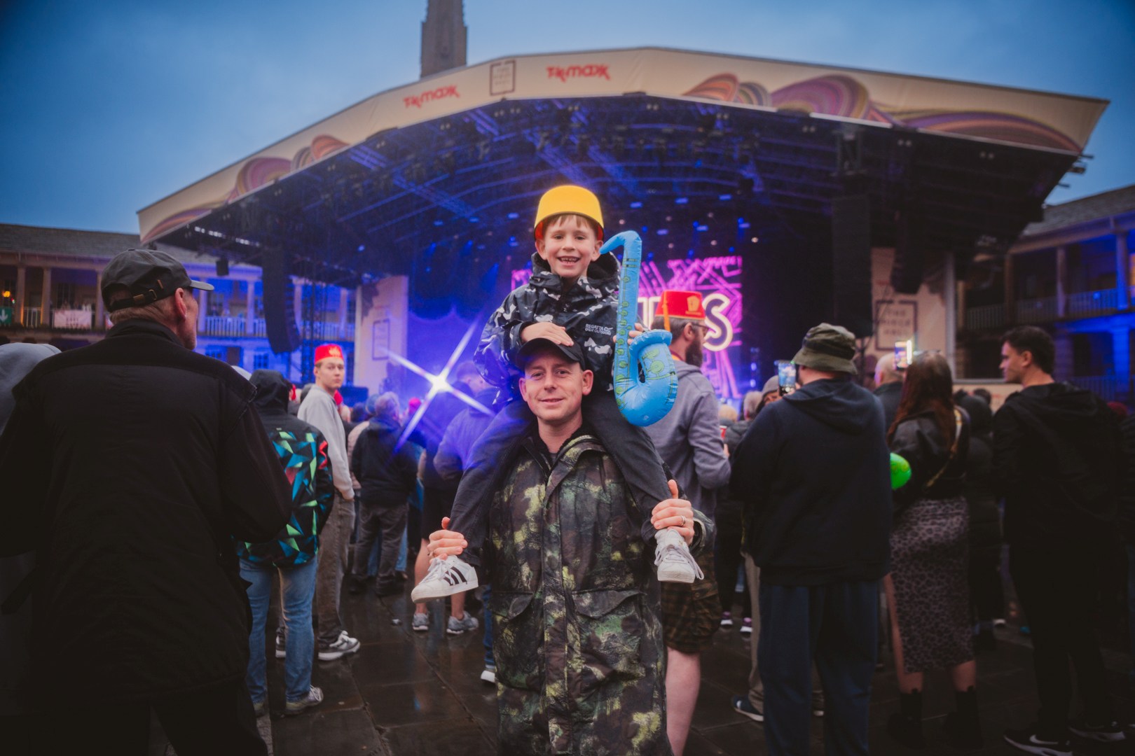Father with son on shoulders at lively outdoor concert