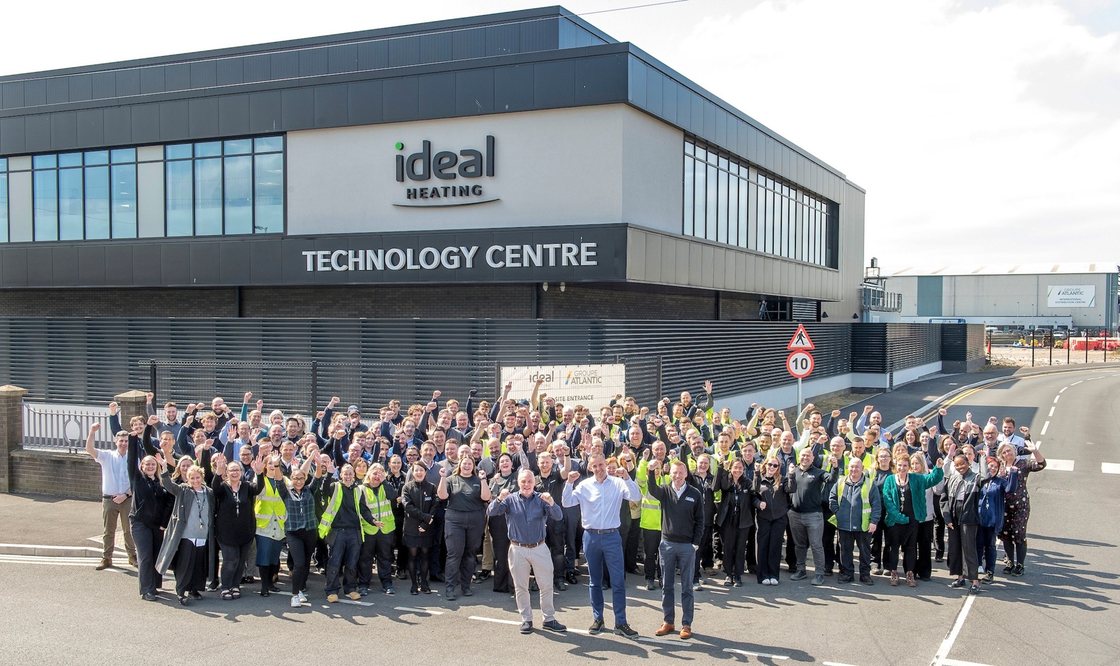 Large group of people outside modern technology center with signage