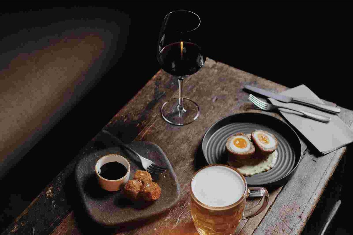 Rustic table with scotch eggs, beer, and red wine
