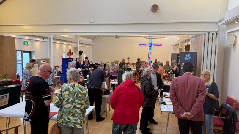 Community event in a church hall with people browsing stalls