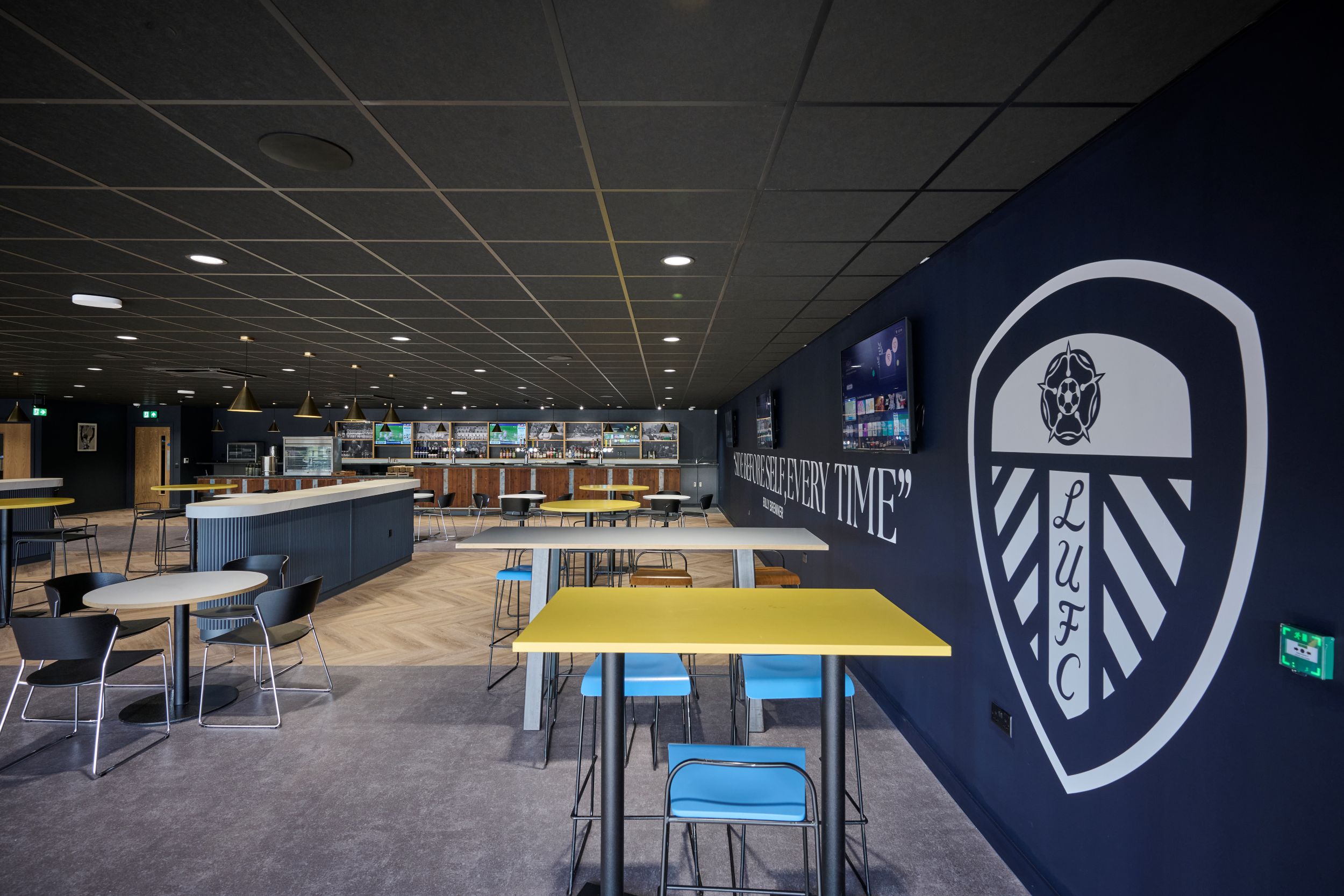 Modern sports bar with Leeds United crest and yellow tables