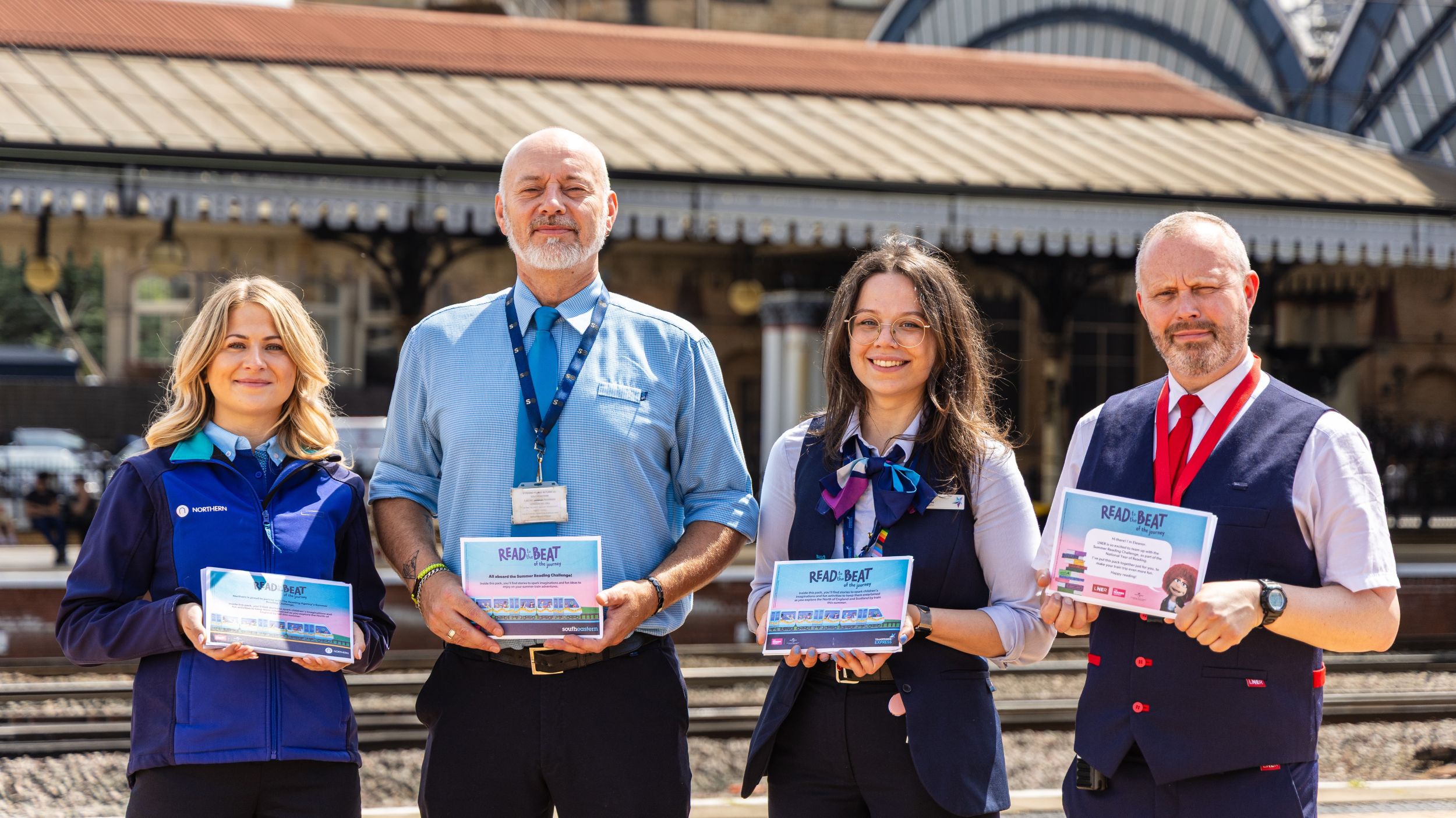 Railway staff holding safety pamphlets at Victorian station