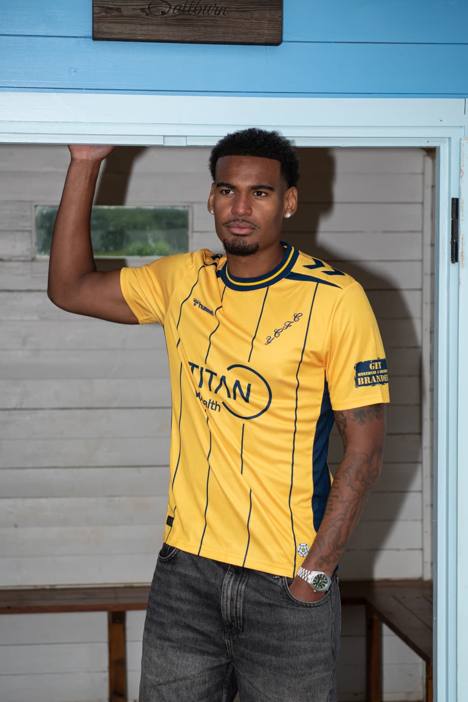 Man in yellow sports jersey standing in wooden doorway
