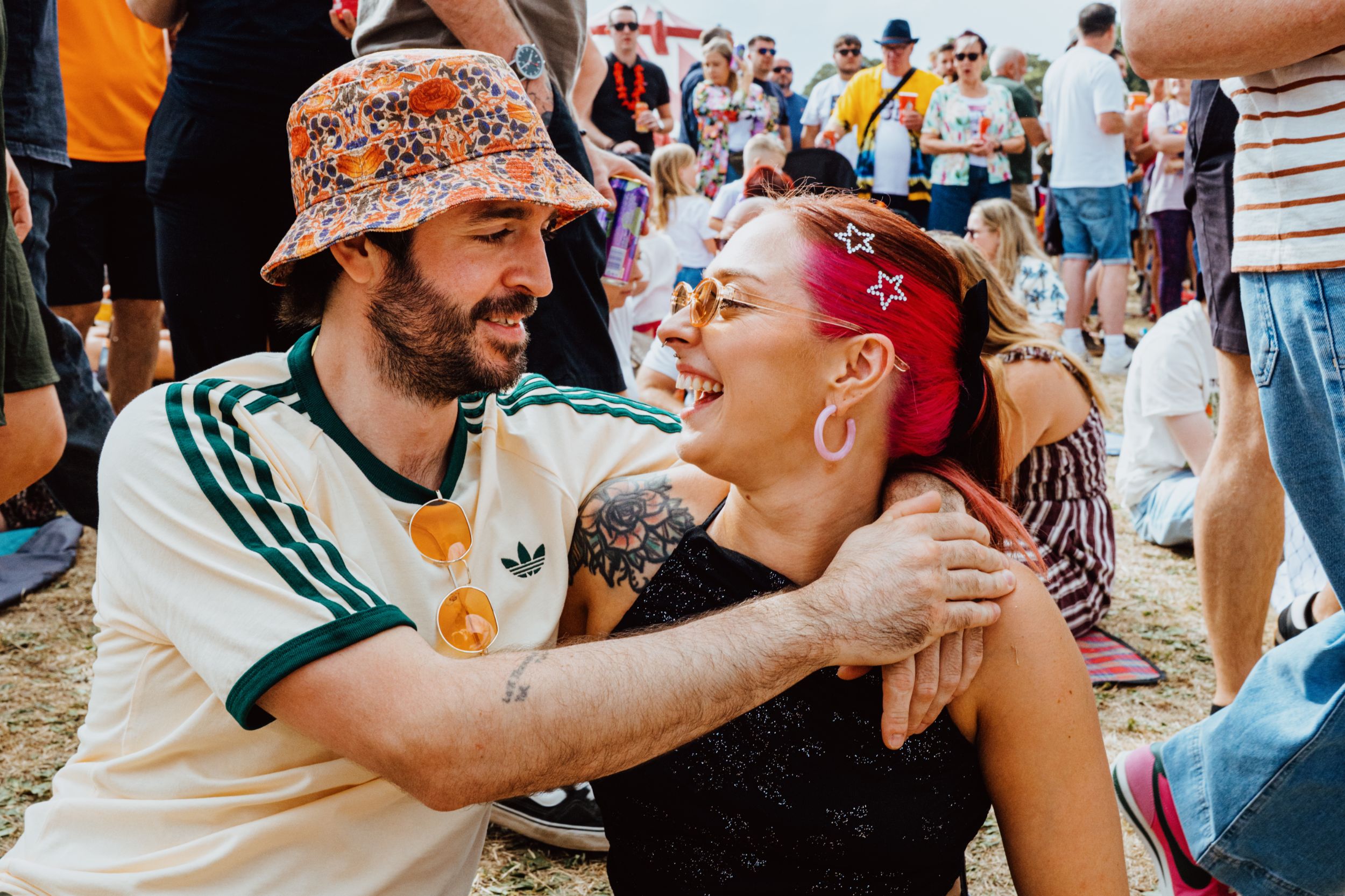 Smiling couple sitting on grass at lively outdoor festival