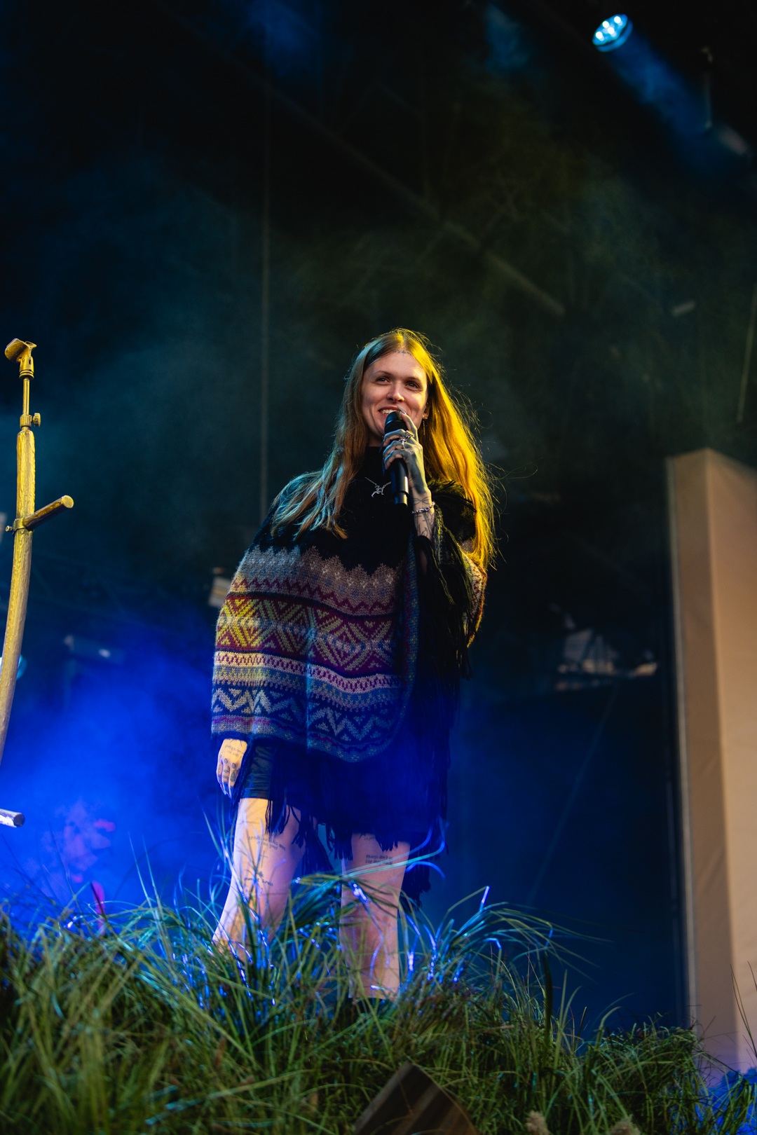 Folk singer in patterned poncho performing on outdoor stage