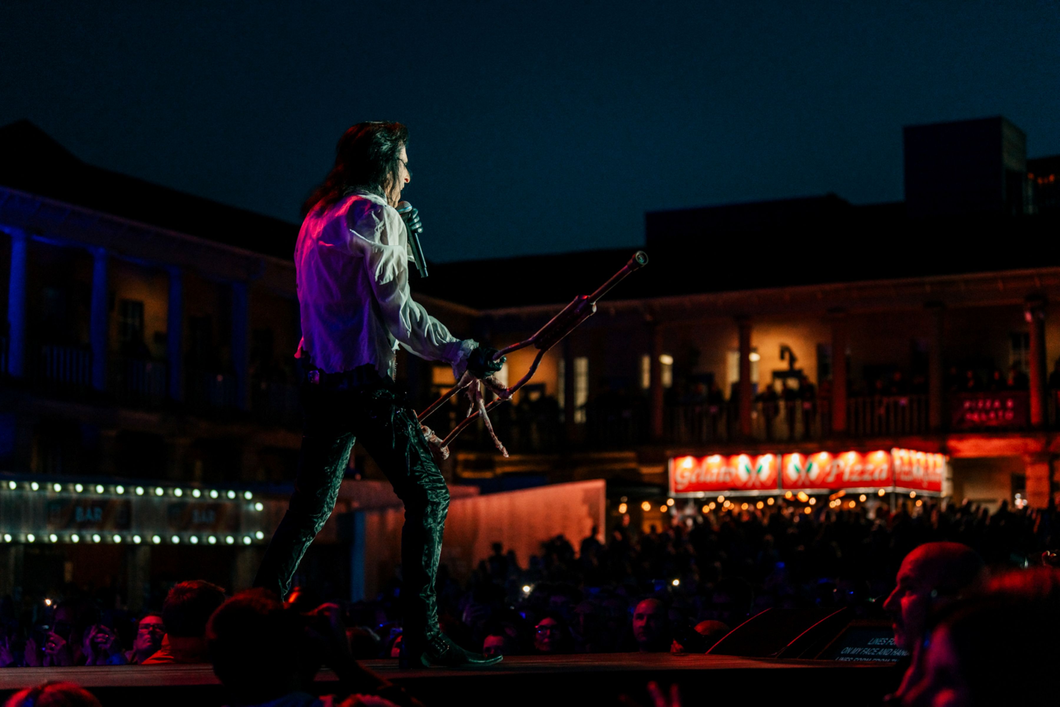 Performer with microphone on stage at outdoor night concert