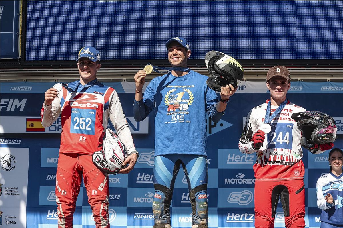 Three motocross riders on podium holding medals and helmets