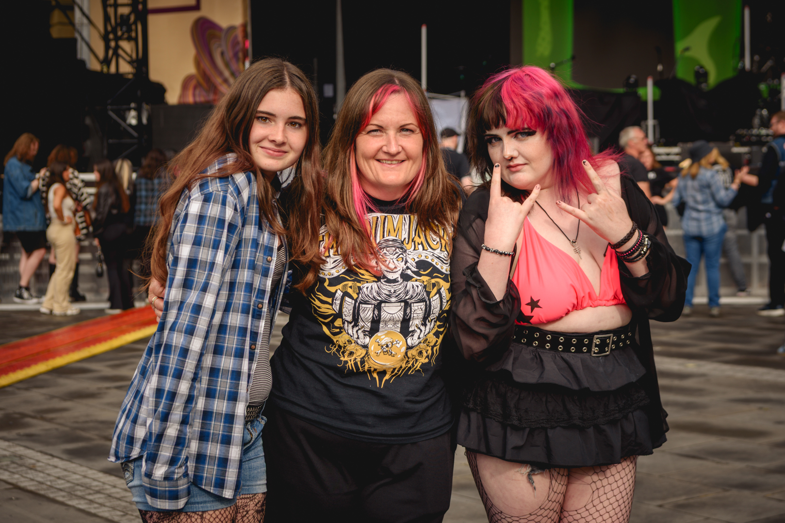 Three women smiling at a music festival with colorful outfits