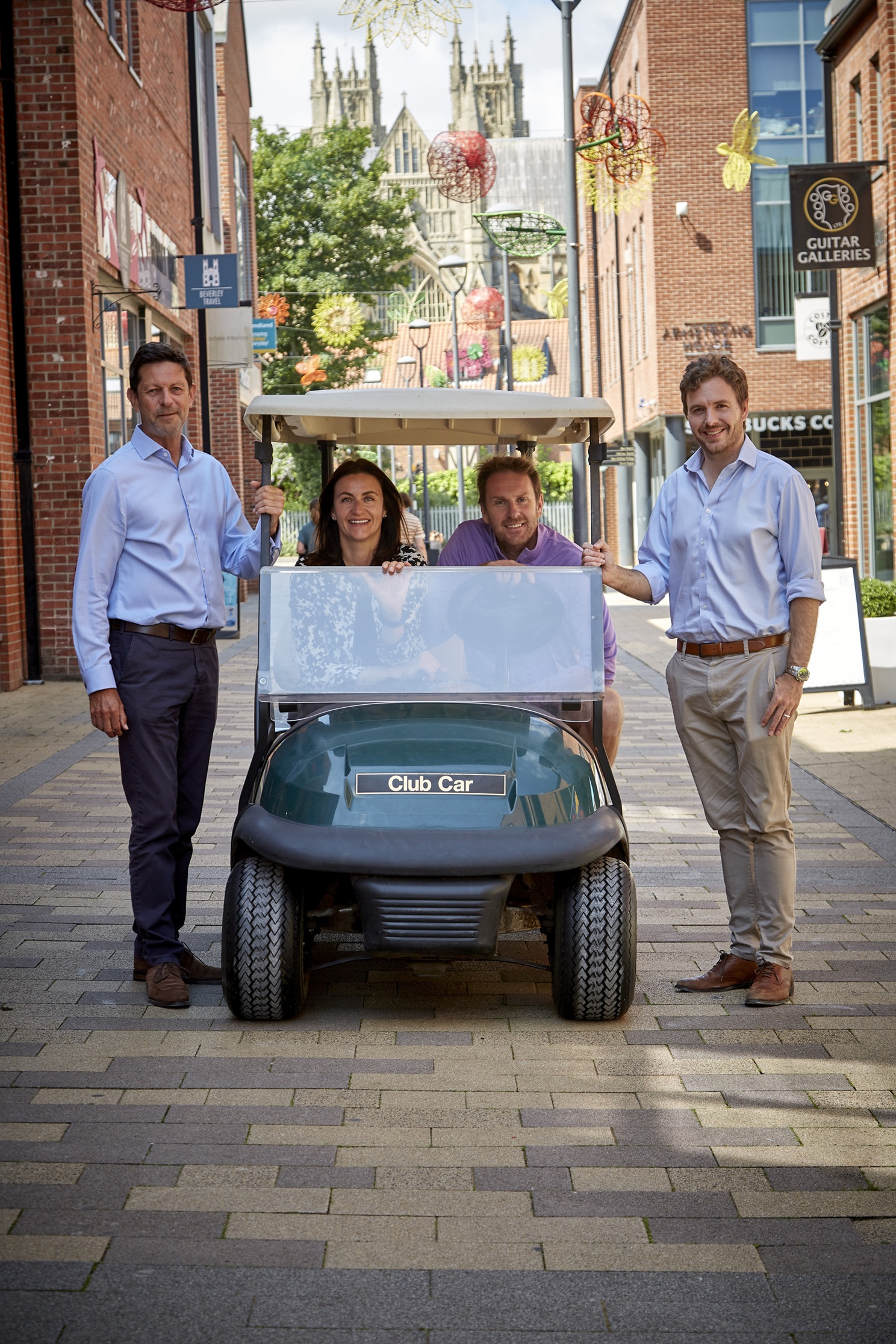 Four people with a golf cart on a cobbled street in York