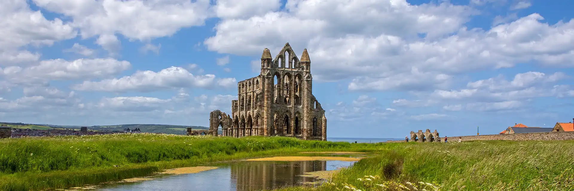 Whitby Abbey ruins on a hill under a cloudy blue sky