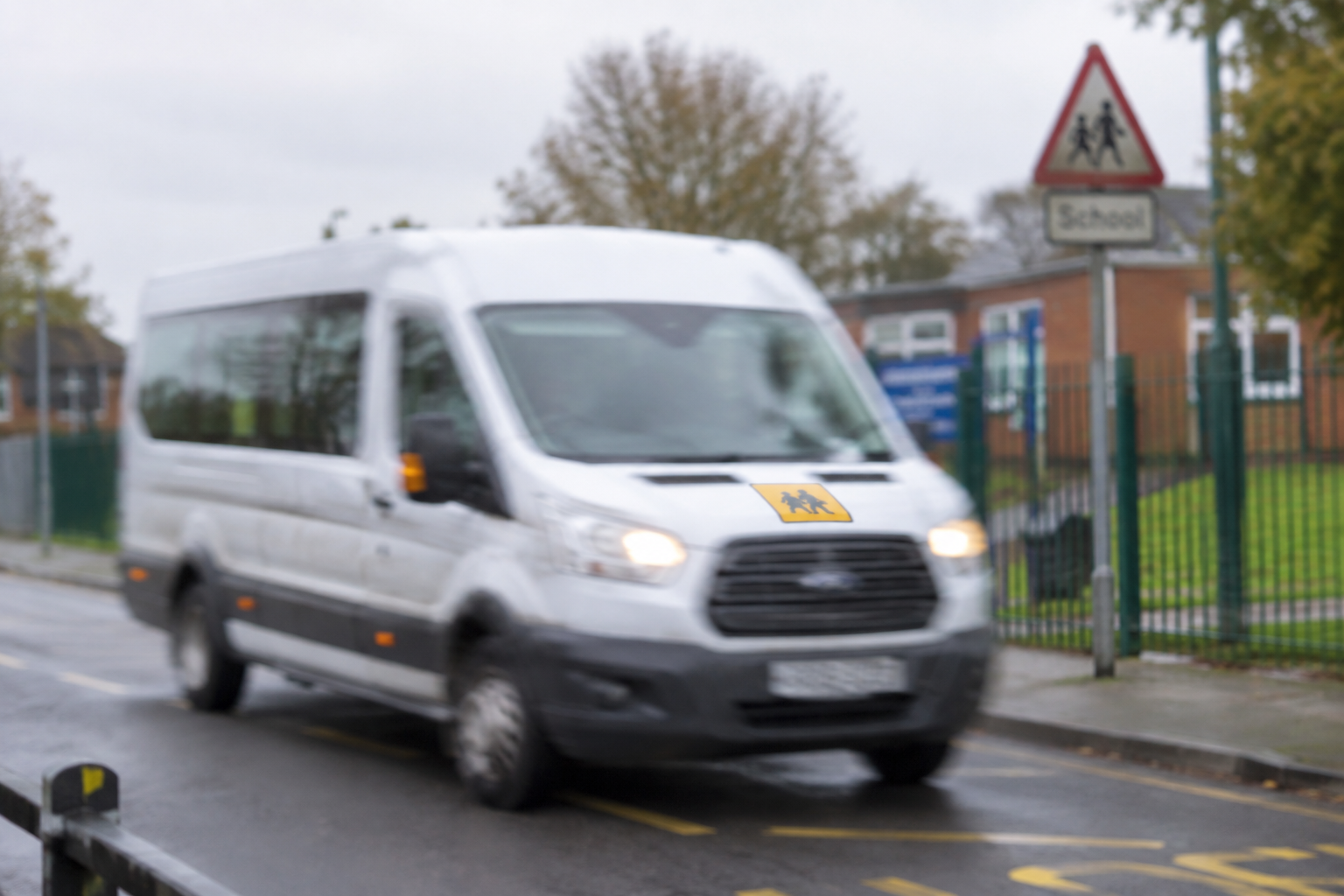 White minibus near school crossing on a rainy day