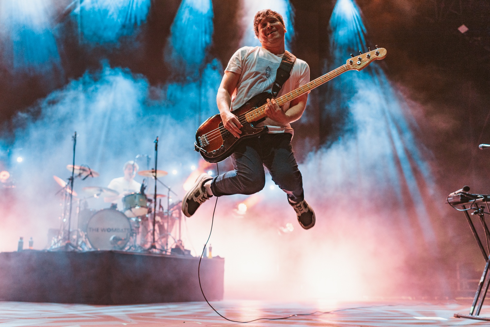 Energetic musician jumping on stage with electric guitar and colourful lights