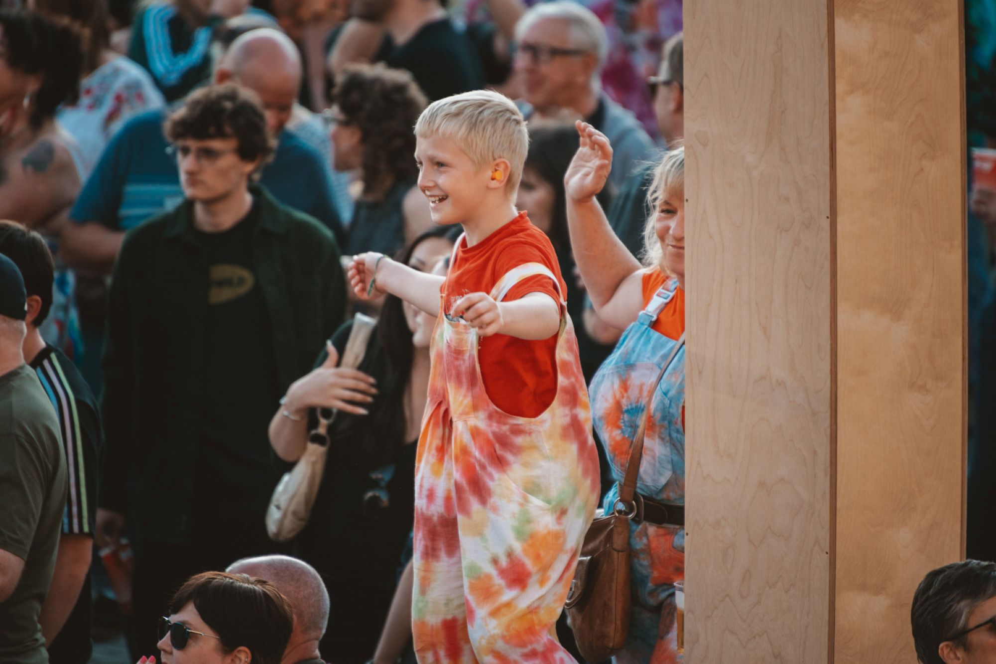Smiling child in colourful tie-dye outfit dancing at outdoor festival