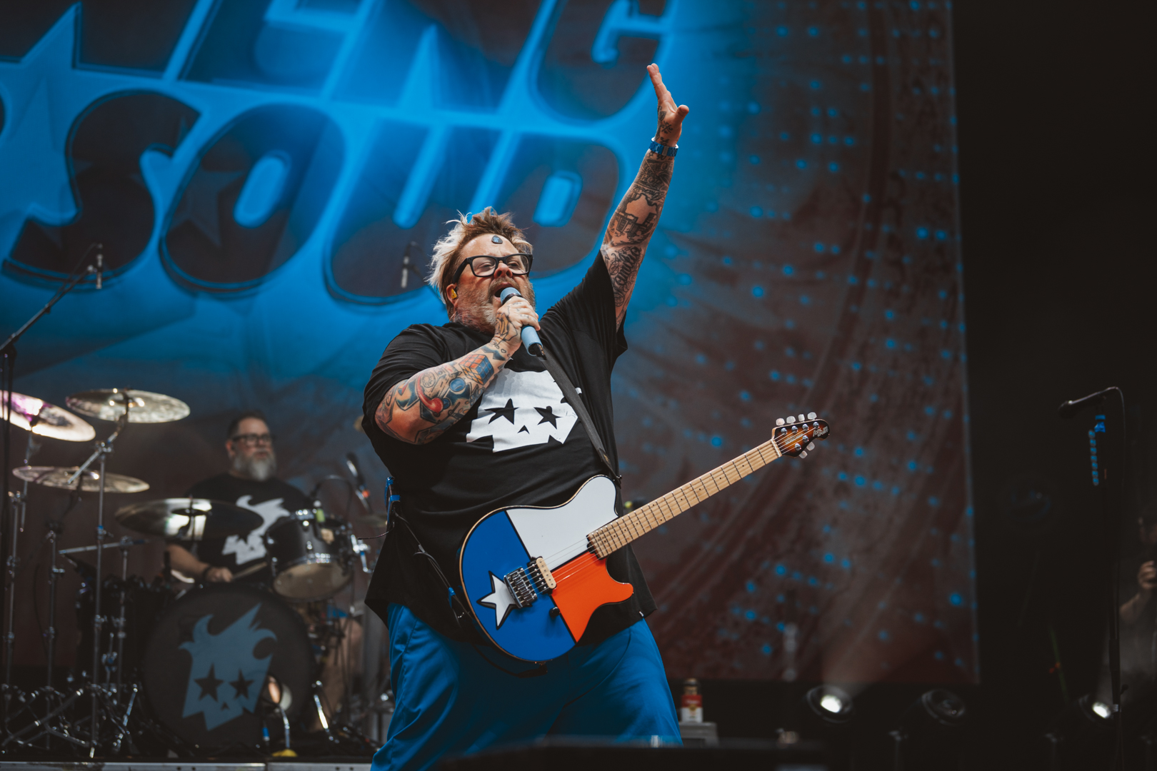 Musician with tattoos performing on stage with guitar