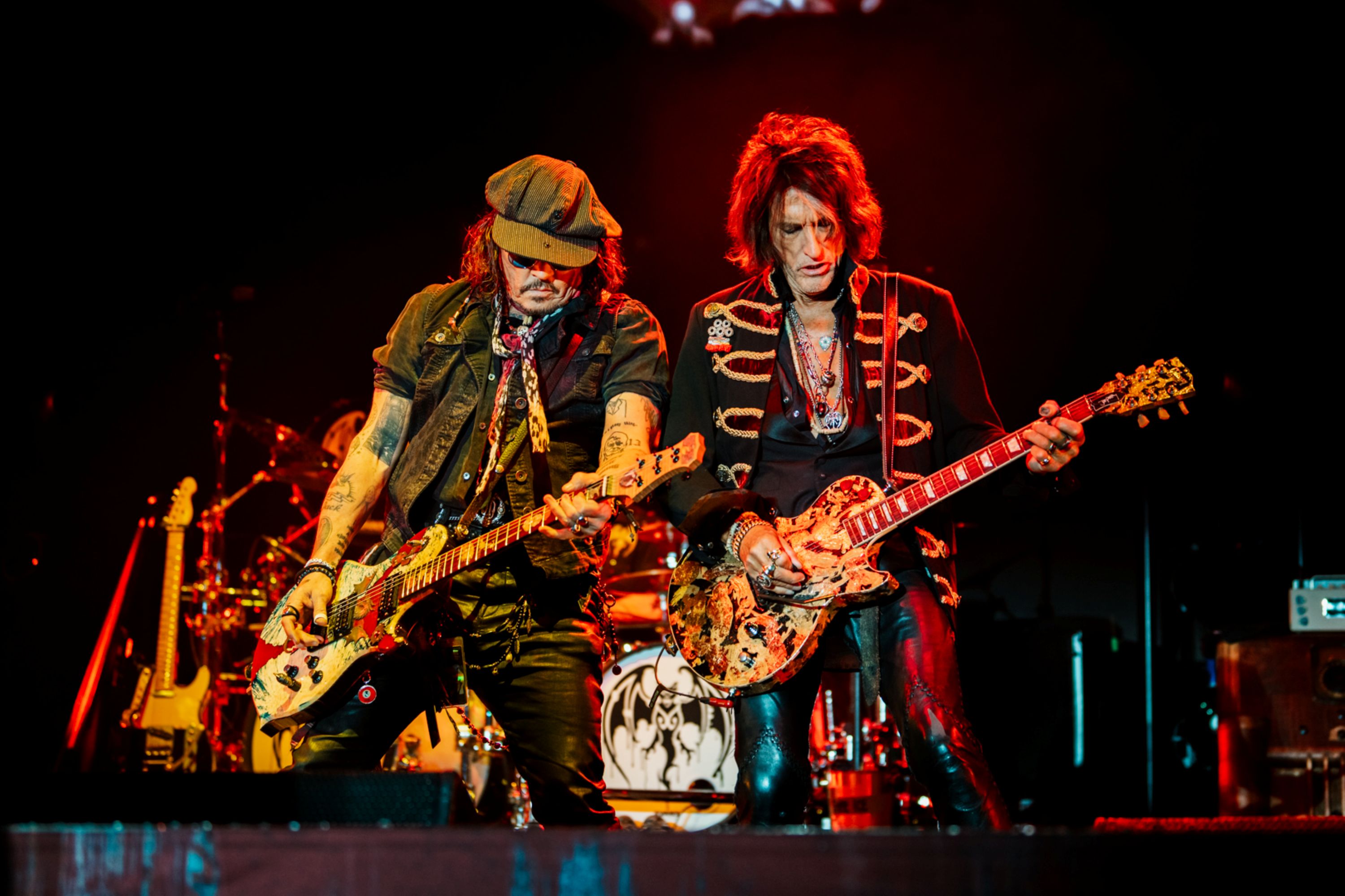 Two musicians playing electric guitars on stage with vibrant lighting