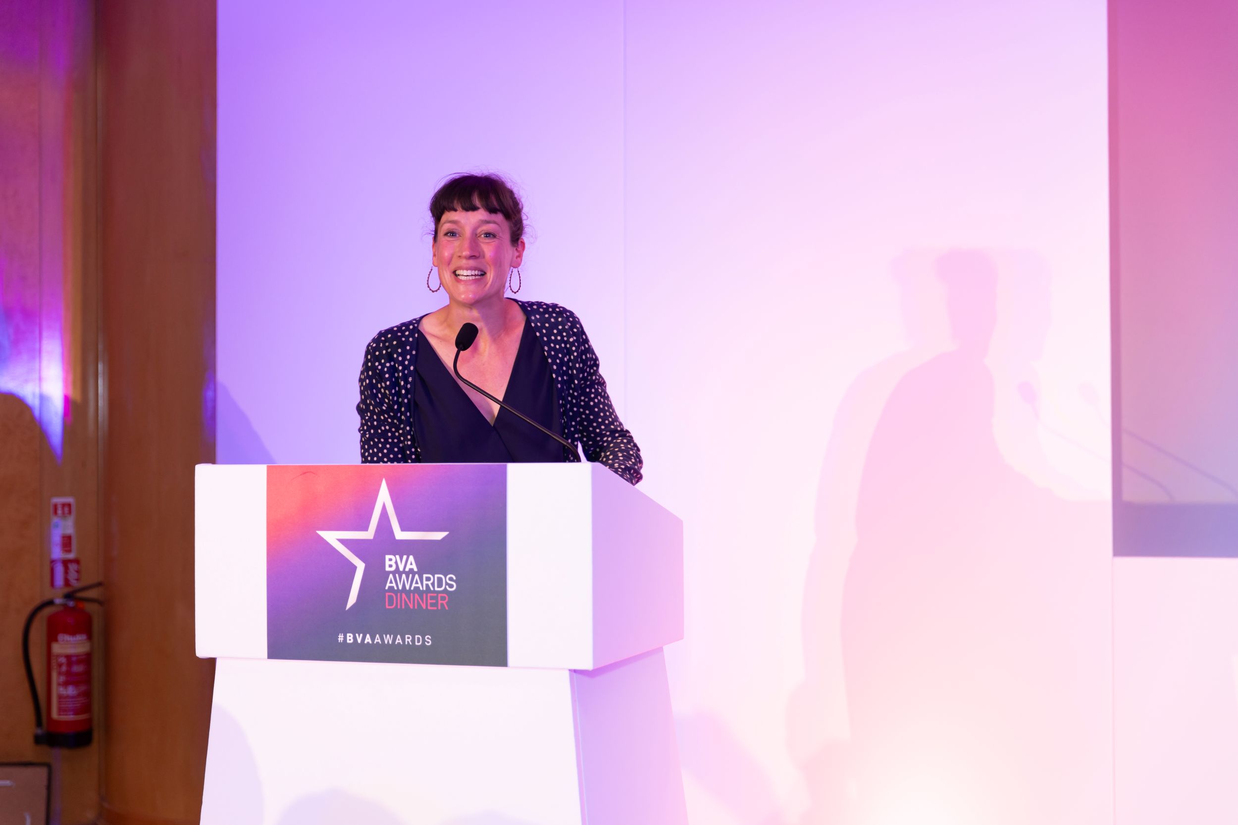 Smiling woman speaking at a podium during an awards event
