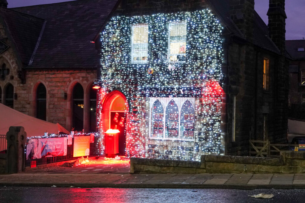 A festively decorated building adorned with twinkling white and red lights, creating a cheerful Christmas atmosphere.