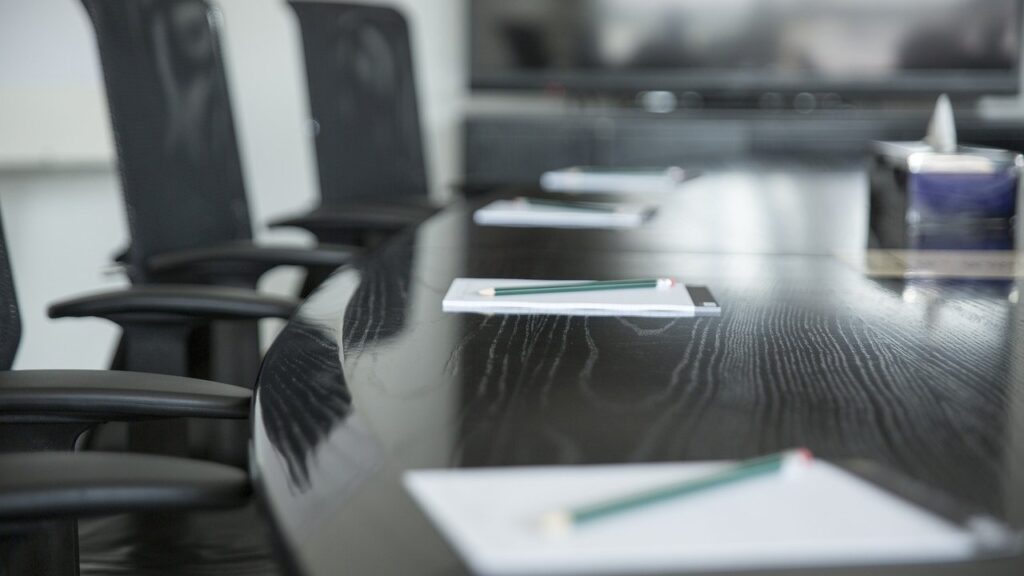 A sleek conference table set with notepads and pencils, surrounded by ergonomic office chairs.