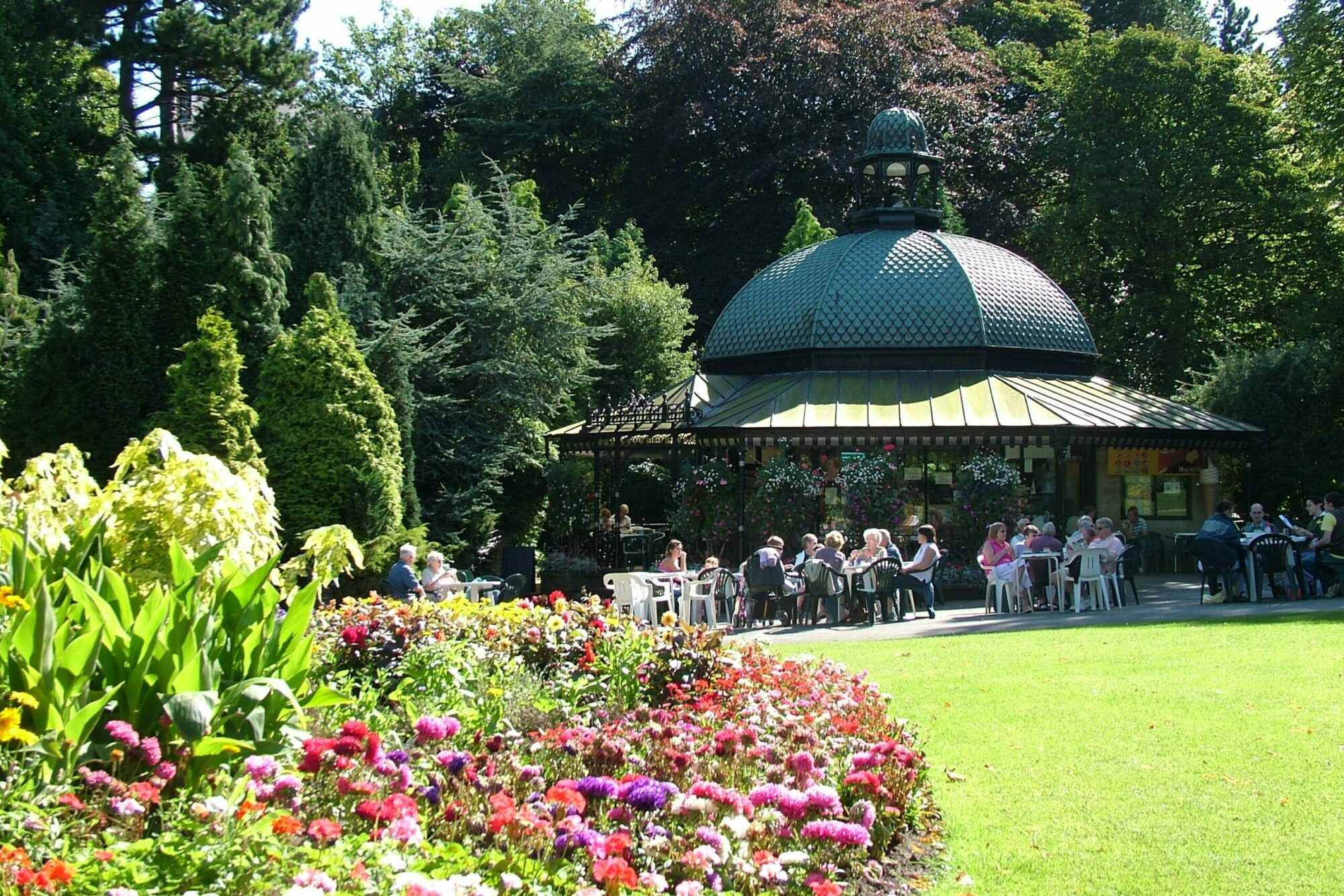 flowers and grass in the park. people sat outside having drinks and snacks. sunshine café