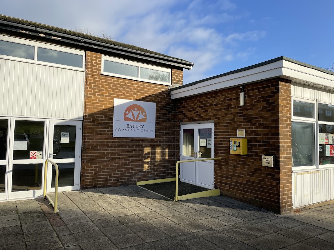 Brick building with large windows, a sign reading "Batley Community Centre," and a ramp for accessibility.