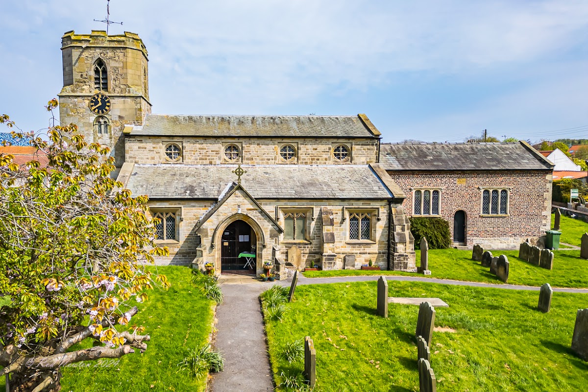 St Michael's Church in Bempton, Yorkshire, featuring stone architecture, a tall clock tower, and a surrounding graveyard.