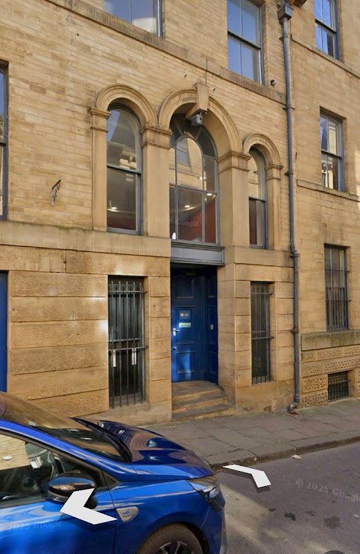 Pay & Display sign on Burnett Street, Bradford, with a stone building and blue car parked nearby.