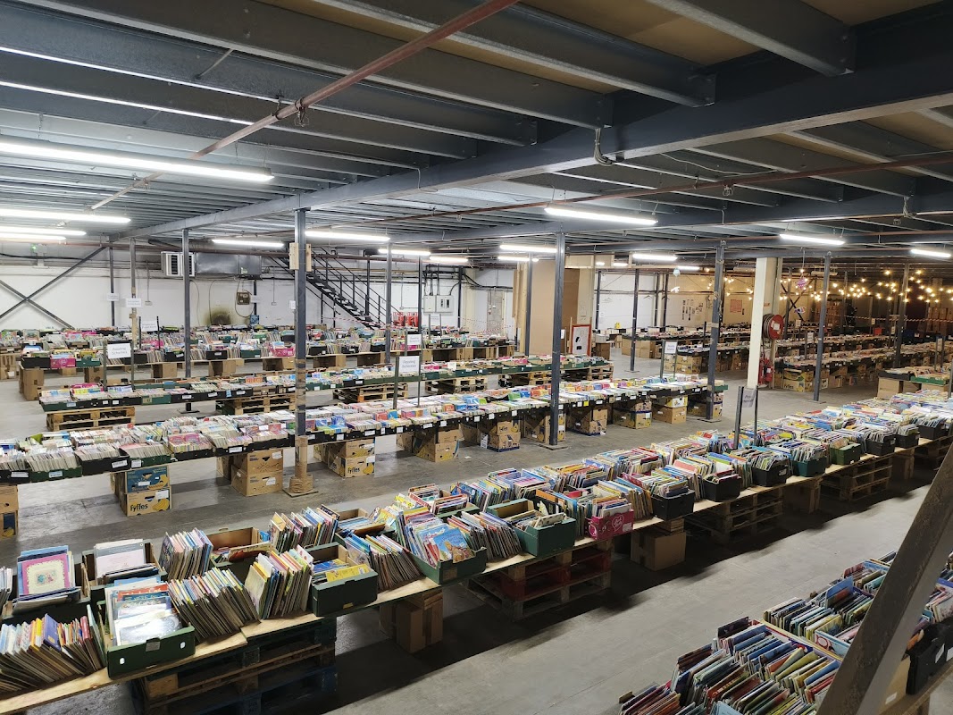 A spacious bookshop with rows of wooden crates filled with colorful books, under industrial-style lighting.