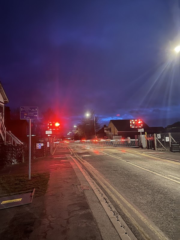 Brough Station Long Stay Car Park entrance at night, with red signal lights and a barrier across the road.
