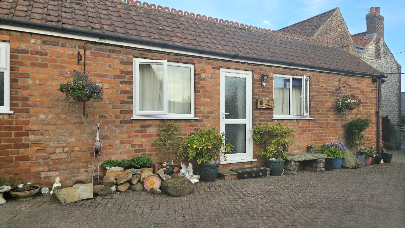 Charming brick exterior of Stables Bed and Breakfast with flower pots, a welcoming door, and decorative stones.
