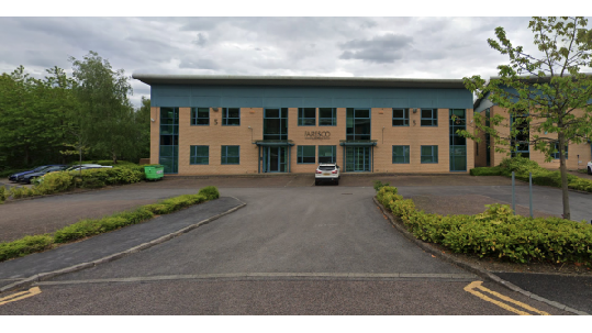 Parking area with a large building, trees, and several parked cars in Chapeltown, Yorkshire.