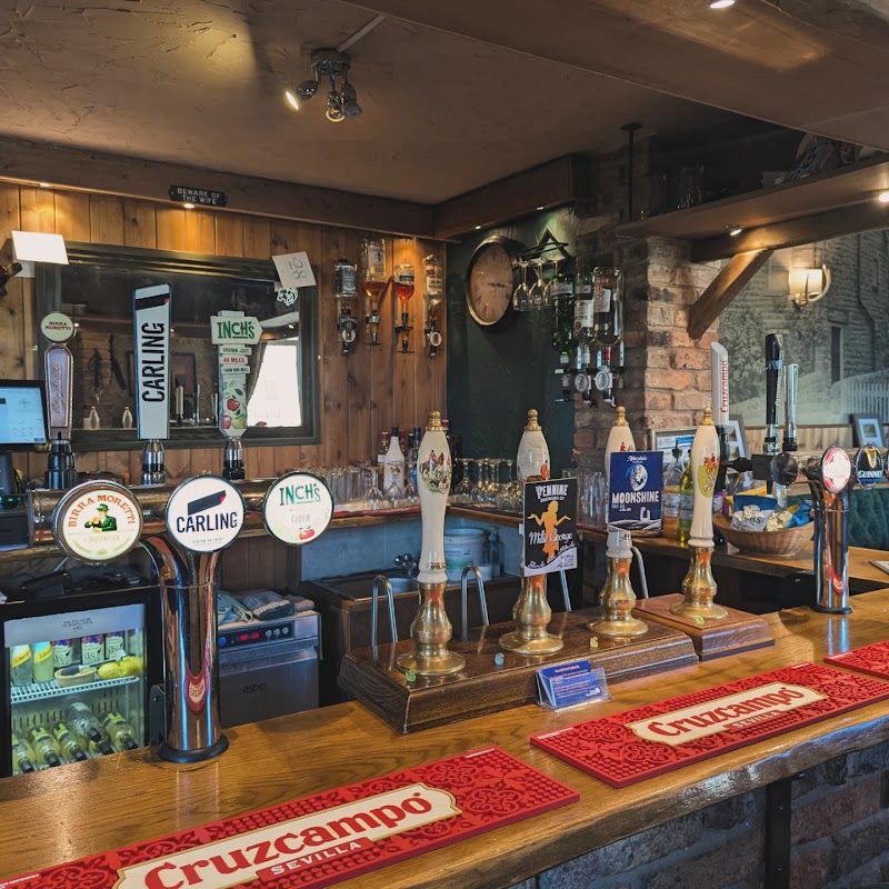Bar counter with various beer taps, a mirror, and shelves displaying drinks in a rustic setting.
