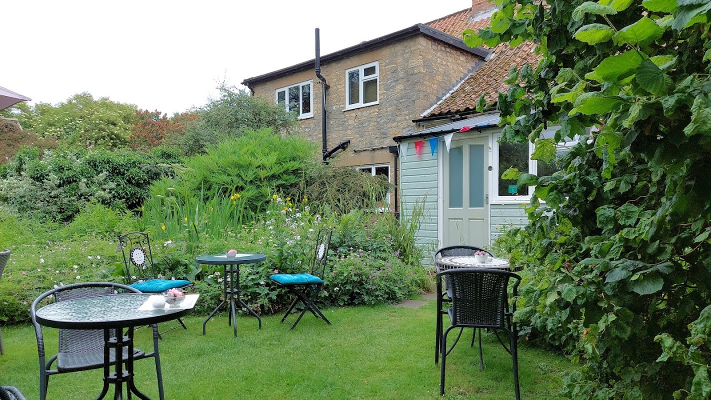 Charming garden with tables and chairs, surrounded by greenery and a quaint building at Coxwold Tearooms.