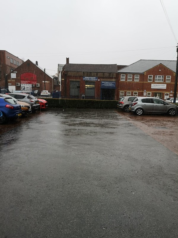 Pay & Display car park in Doncaster, wet pavement, parked cars, buildings in the background, overcast sky.