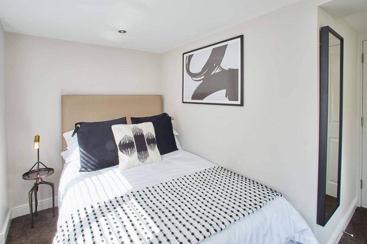 Cozy bedroom in Dunsley Chapel cottage, Yorkshire, with modern decor, abstract art, and a soft, inviting bed.