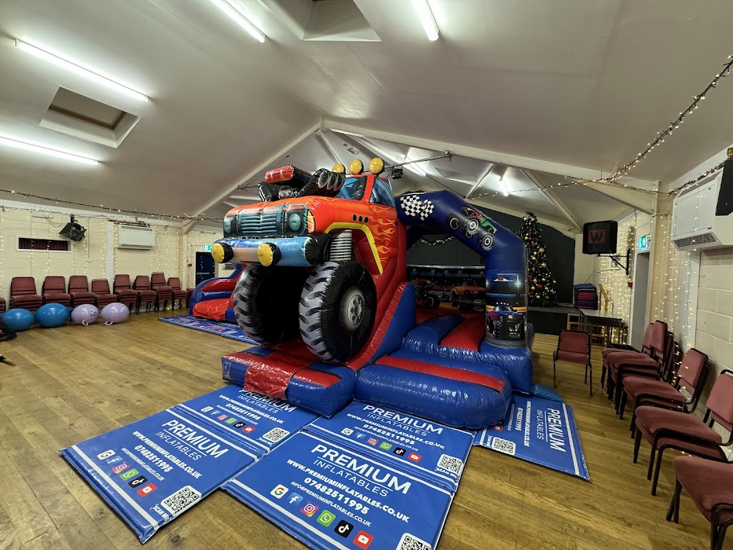 Brightly colored inflatable truck bouncer in a community hall with chairs and festive decorations.