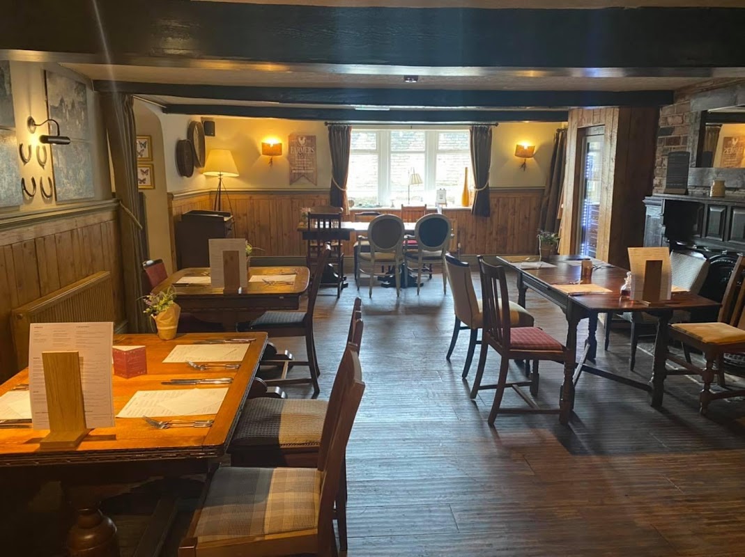 Cozy bar interior with wooden tables, chairs, and warm lighting, featuring a rustic ambiance and wall art.