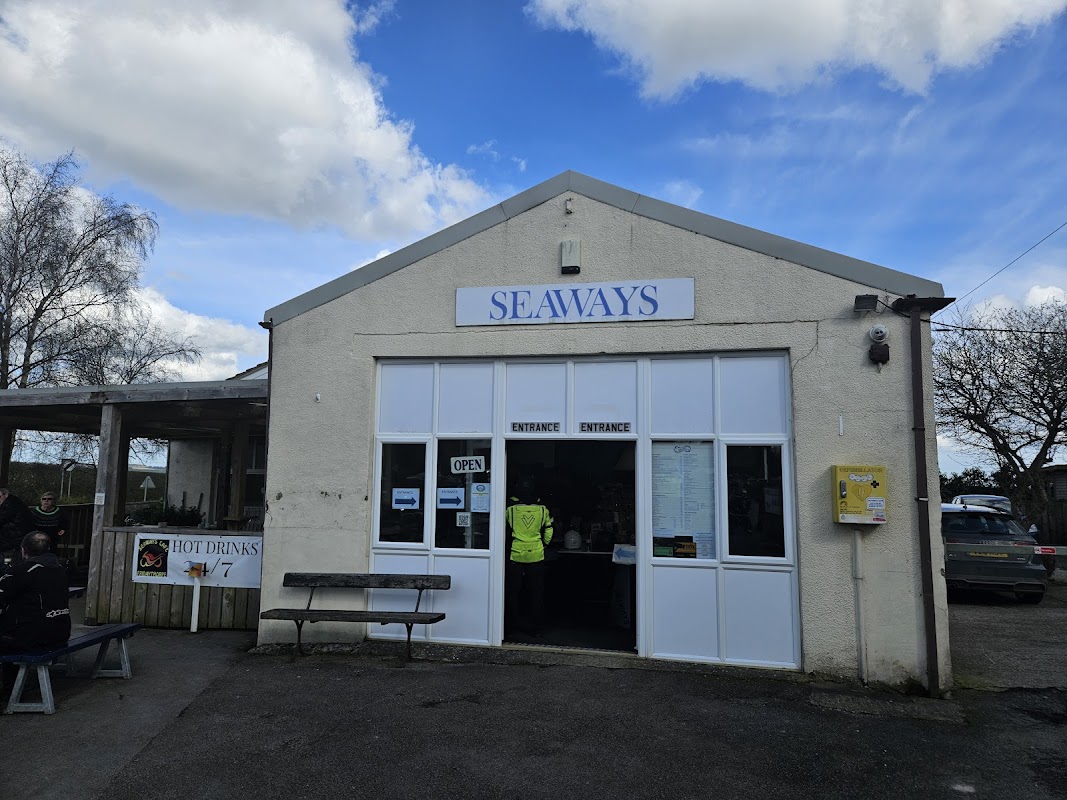 Seaways building with a large sign, open entrance, and outdoor seating area under a cloudy sky.
