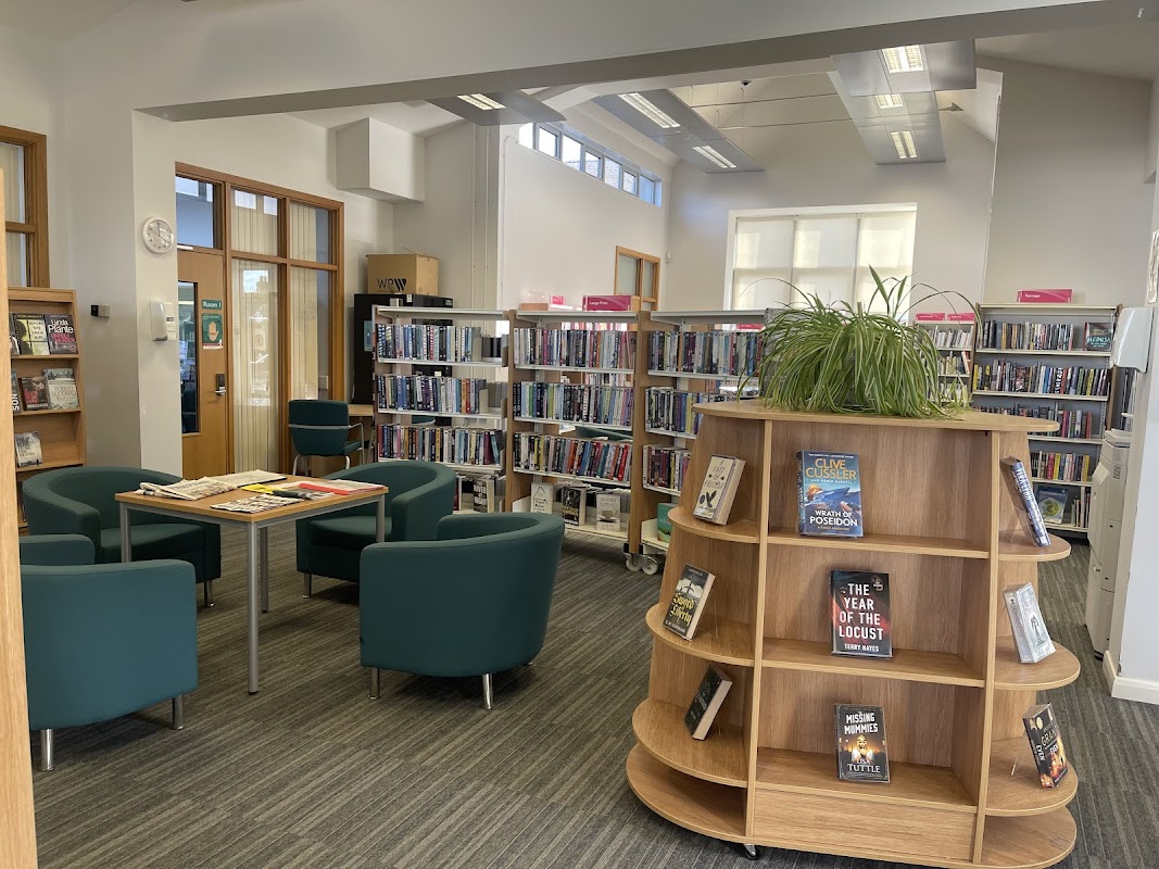 Bright interior of Driffield Library with bookshelves, seating area, and a wooden display stand for books.