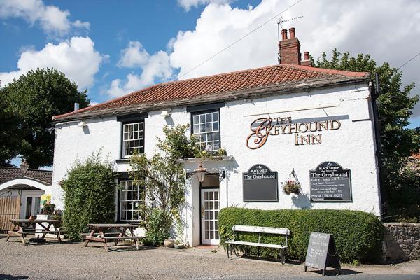 Charming Bed & Breakfast with white exterior, red roof, outdoor seating, and lush greenery in Hackforth, Yorkshire.