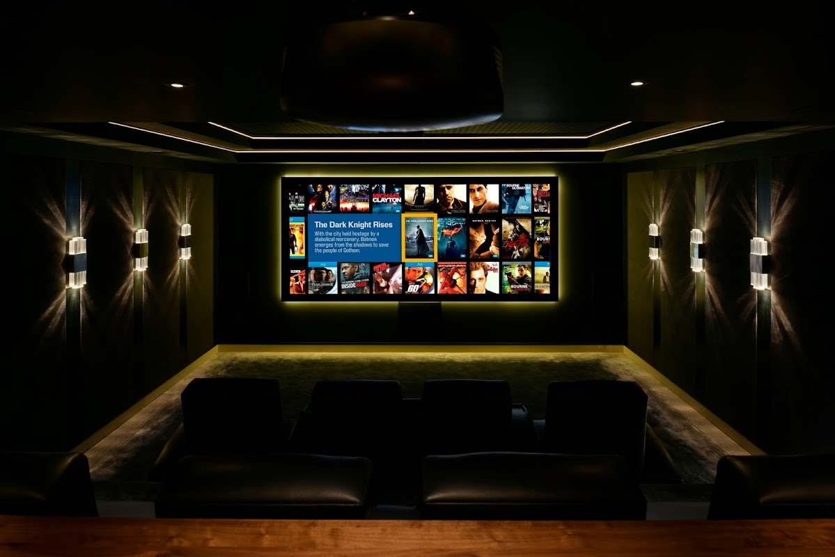 A modern home theater with a large screen displaying movie posters, dark walls, and plush seating.