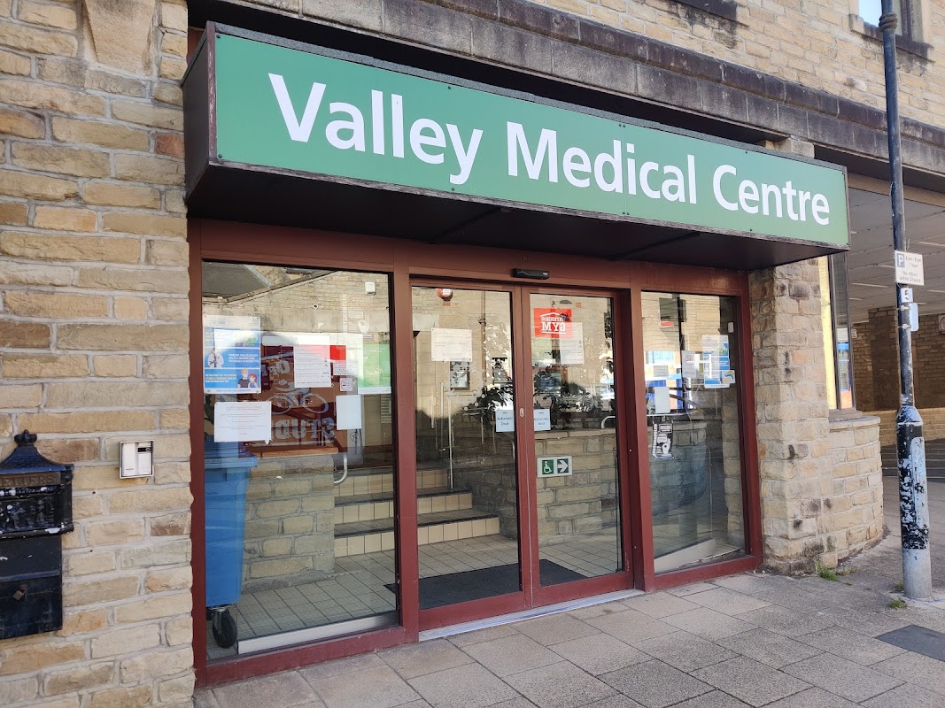 Entrance of Valley Medical Centre with glass doors, stone walls, and signage in green.