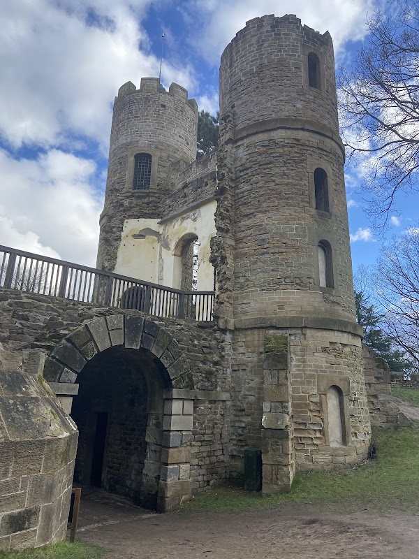 Ruins of Stainborough Castle with stone towers and archways, set against a blue sky with scattered clouds.
