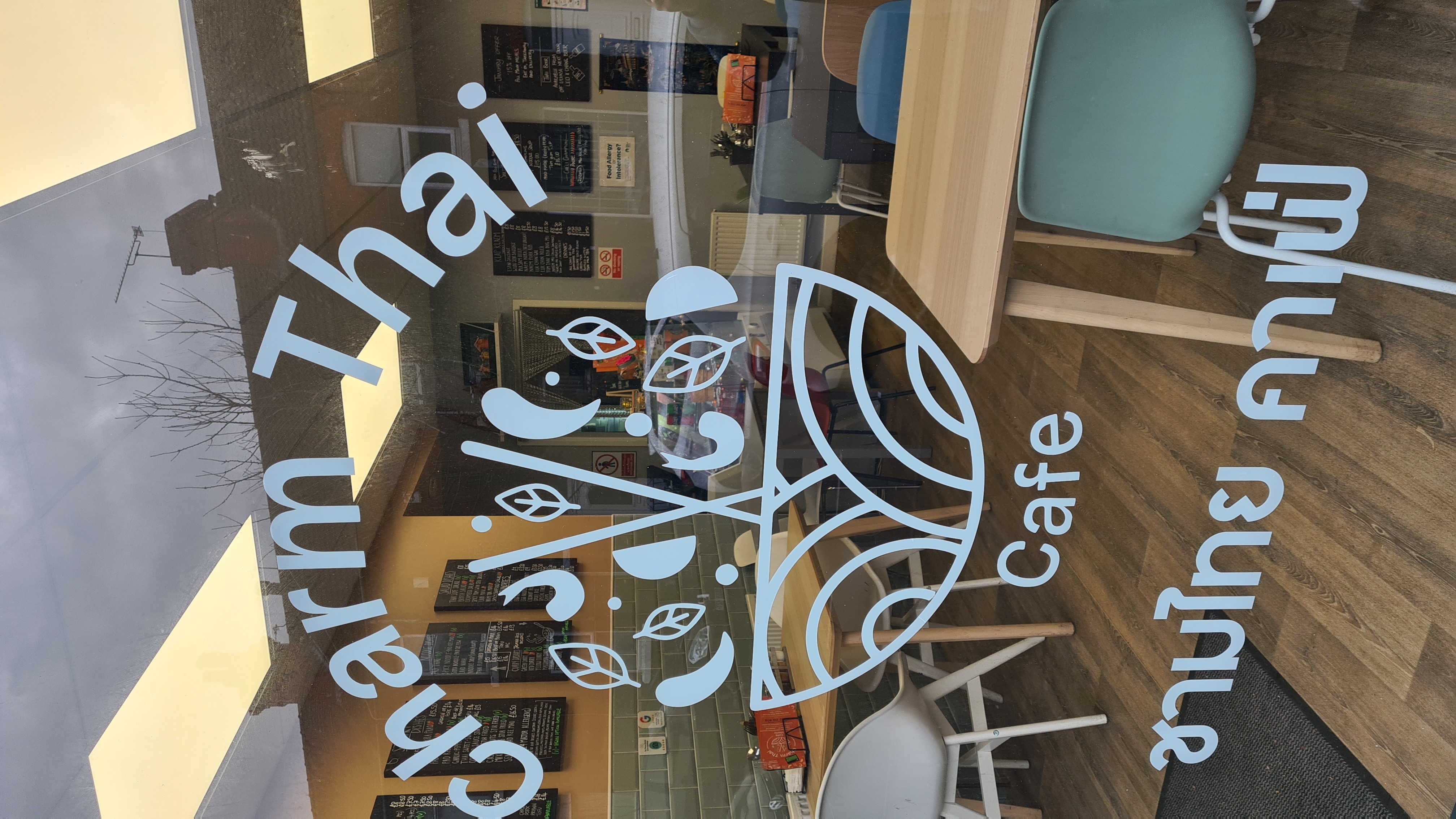 Cozy cafe interior with wooden floors, modern decor, and large logo on the window