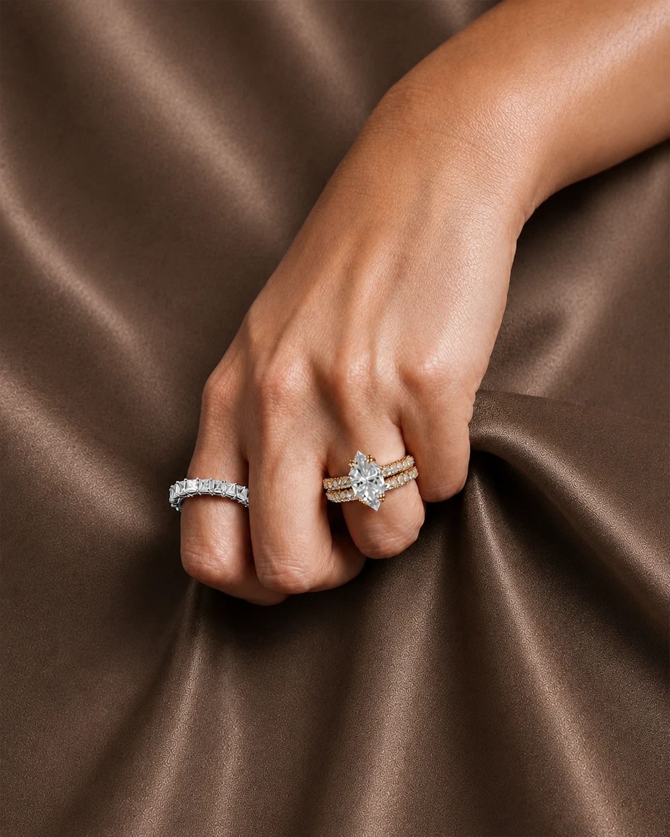 Hand displaying elegant diamond rings on a silky brown fabric
