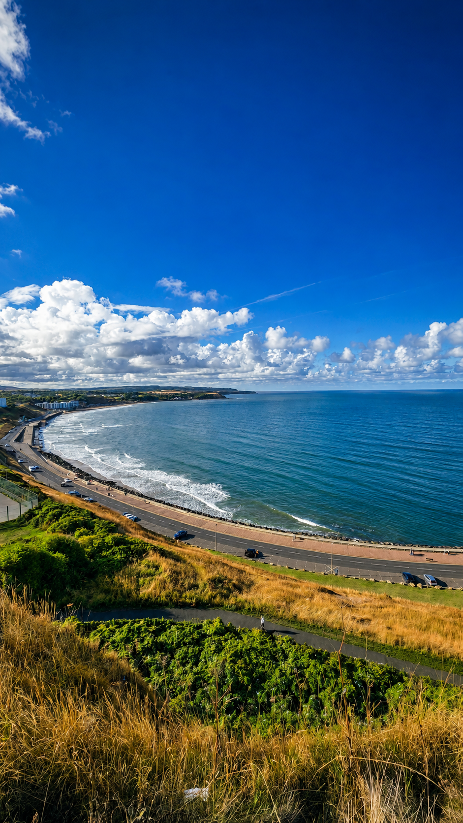 Scenic coastal Scarborough view with winding road and expansive sea under a bright blue sky